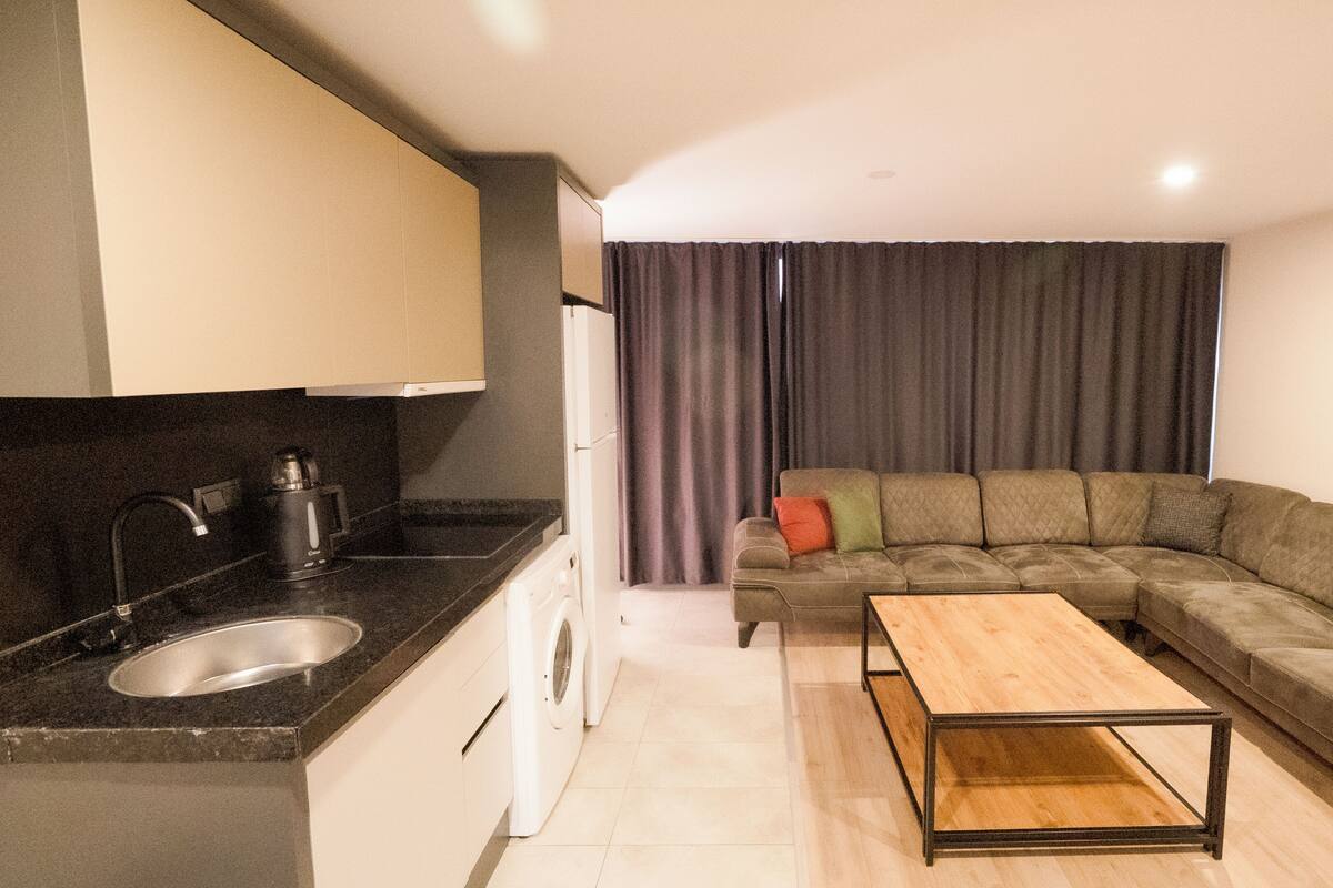 A compact living space with a kitchenette, a sofa, and a coffee table.