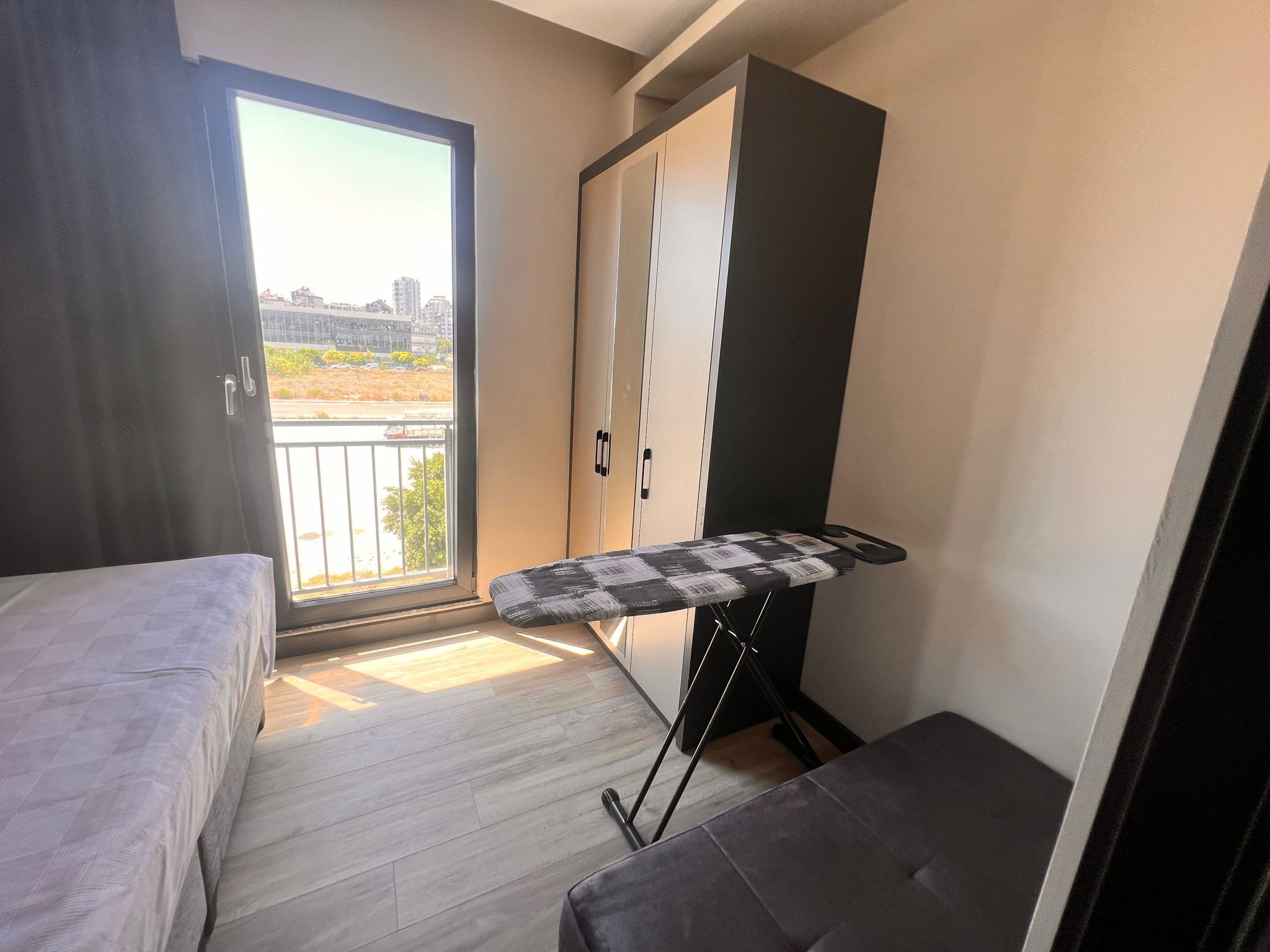 A bedroom with a bed, an ironing board, and a wardrobe.