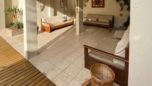 Een ruime woonruimte met een groot bed, een bank en een houten terras.