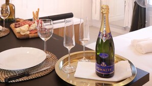 A hotel room with a dining table set for a meal, a bottle of champagne, and a fireplace in the background. - La Marquise Cosy Flat - Jacuzzi - Senlis (Senlis)