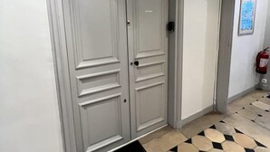 A hallway with a double door, a fire extinguisher, and a patterned floor. - La Marquise Cosy Flat - Jacuzzi - Senlis (Senlis)