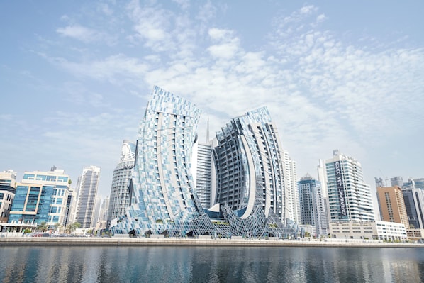 A modern cityscape with distinctive curved skyscrapers and a waterfront. - Lusso Hometels J One (Dubai)
