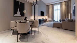 A modern living room with a dining area, a sofa, and a TV mounted on the wall. - Lusso Hometels J One (Dubai)