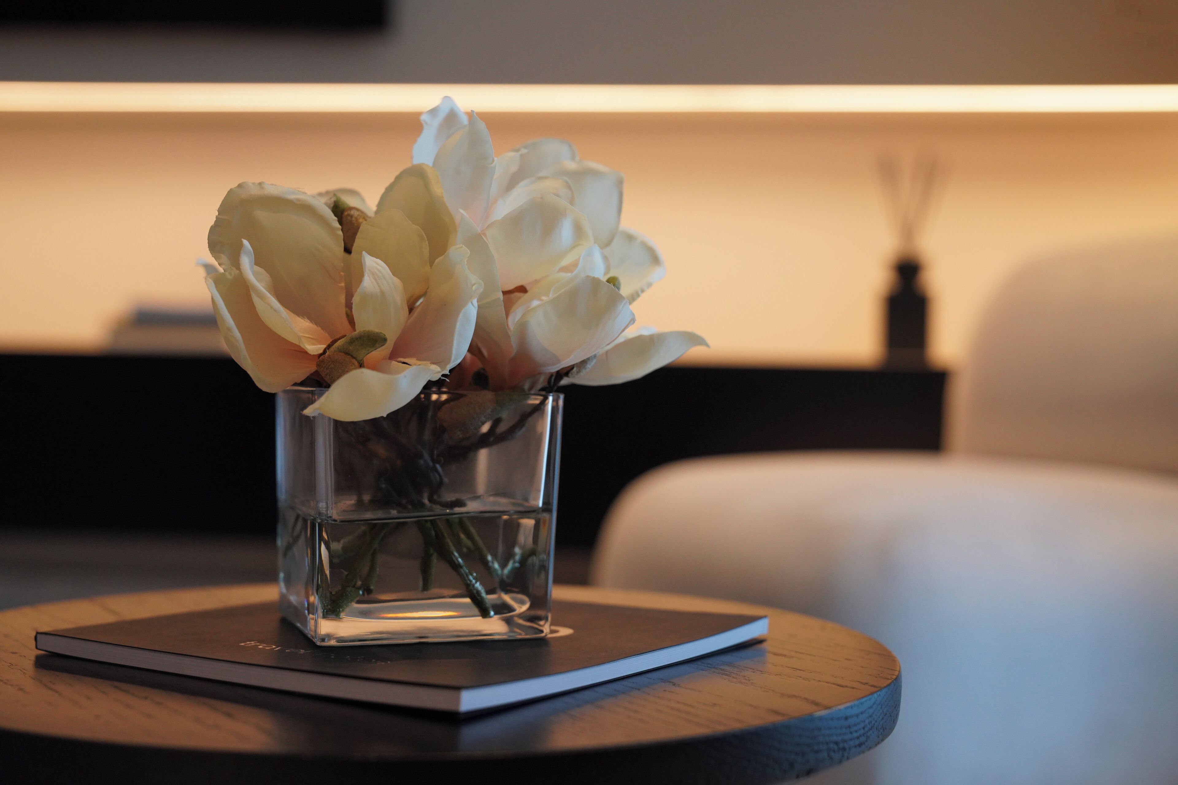 A clear glass vase with white flowers on a wooden table.