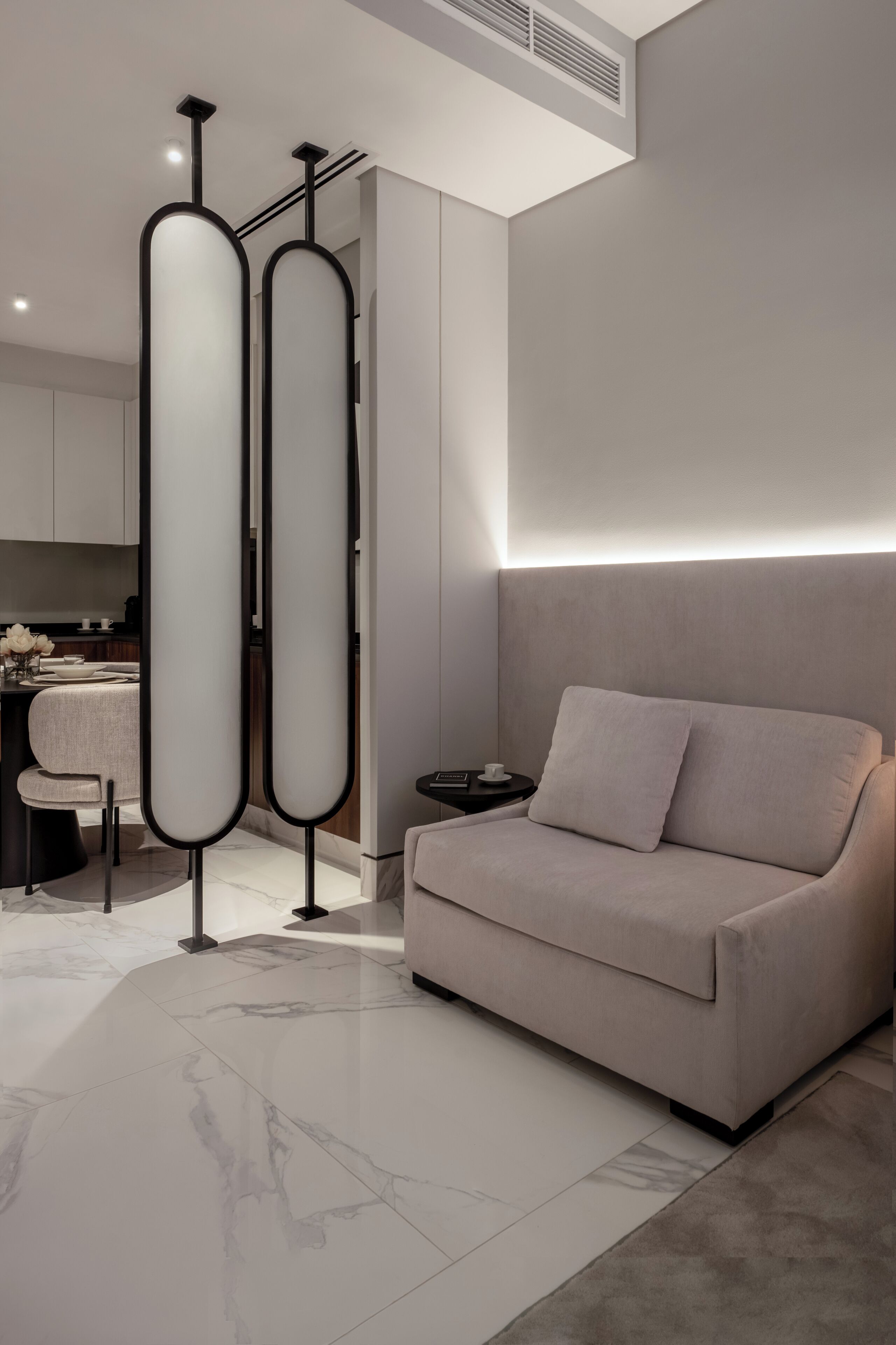 A modern living room with a sofa, a coffee table, and a decorative black and white partition.