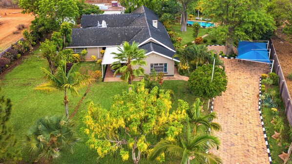 Una propiedad residencial con una casa, piscina y un patio cubierto.