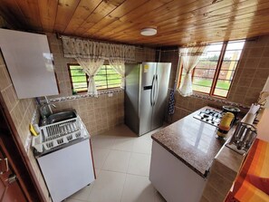 Compact kitchen with a refrigerator, sink, and gas stove, offering ample space for cooking and meal preparation.