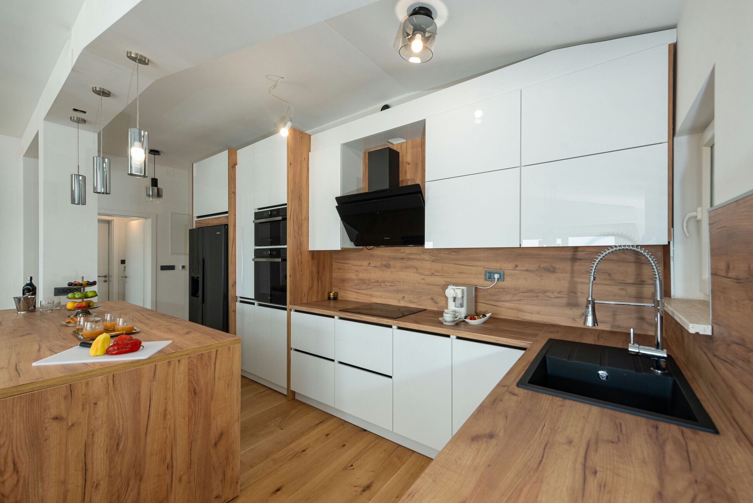 Una cocina moderna con armarios blancos, una encimera de madera y un lavamanos negro.