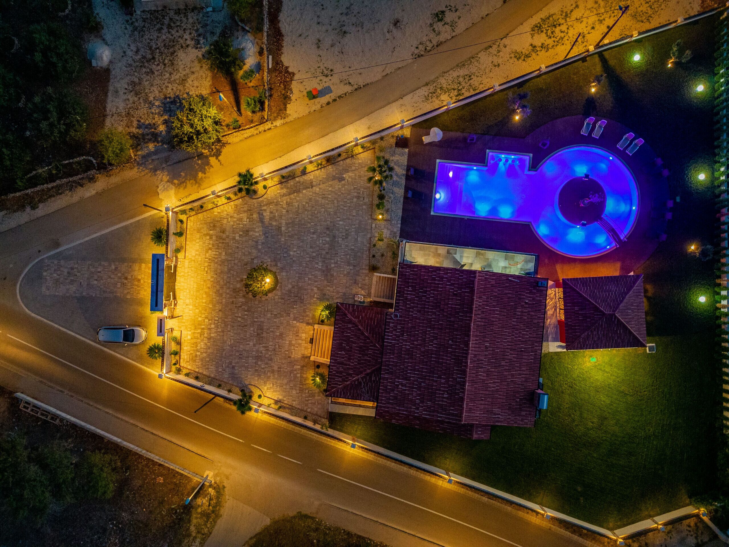 Vista aérea de un hotel con piscina, estacionamiento y una carretera.