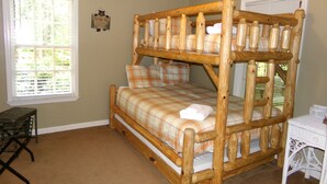 A bunk bed with a plaid bedspread, a small table, and a wicker chair in a room with wooden ceiling and a window with blinds. - Private retreat at the waters edge of one of NE Ga premier trout streams. (Cleveland)