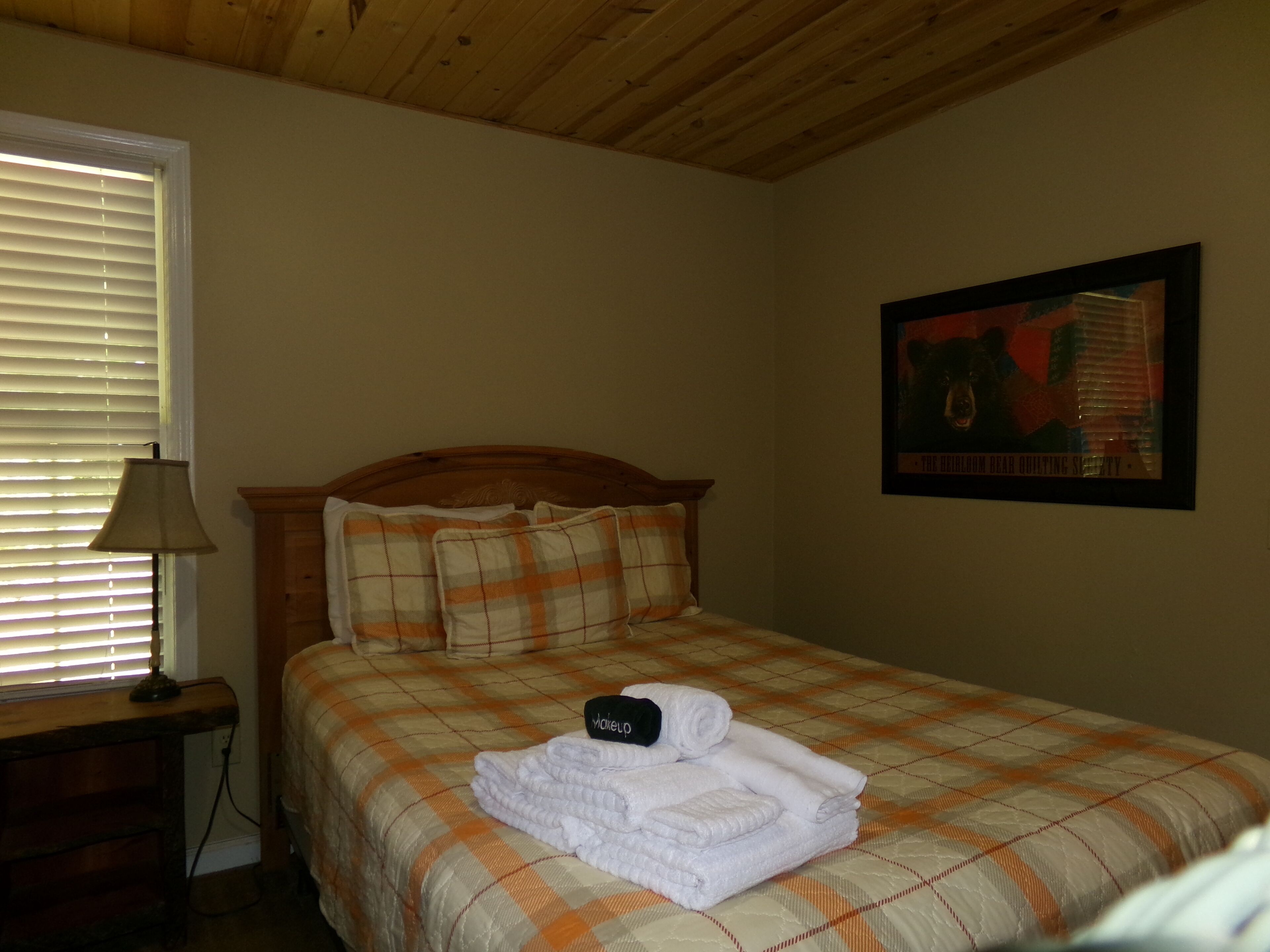 Un dormitorio con una cama, una mesita de noche, una lámpara y un cuadro en la pared.