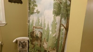 A bathroom with a forest-themed shower curtain, a wooden cabinet, and a wall-mounted towel rack. - Private retreat at the waters edge of one of NE Ga premier trout streams. (Cleveland)