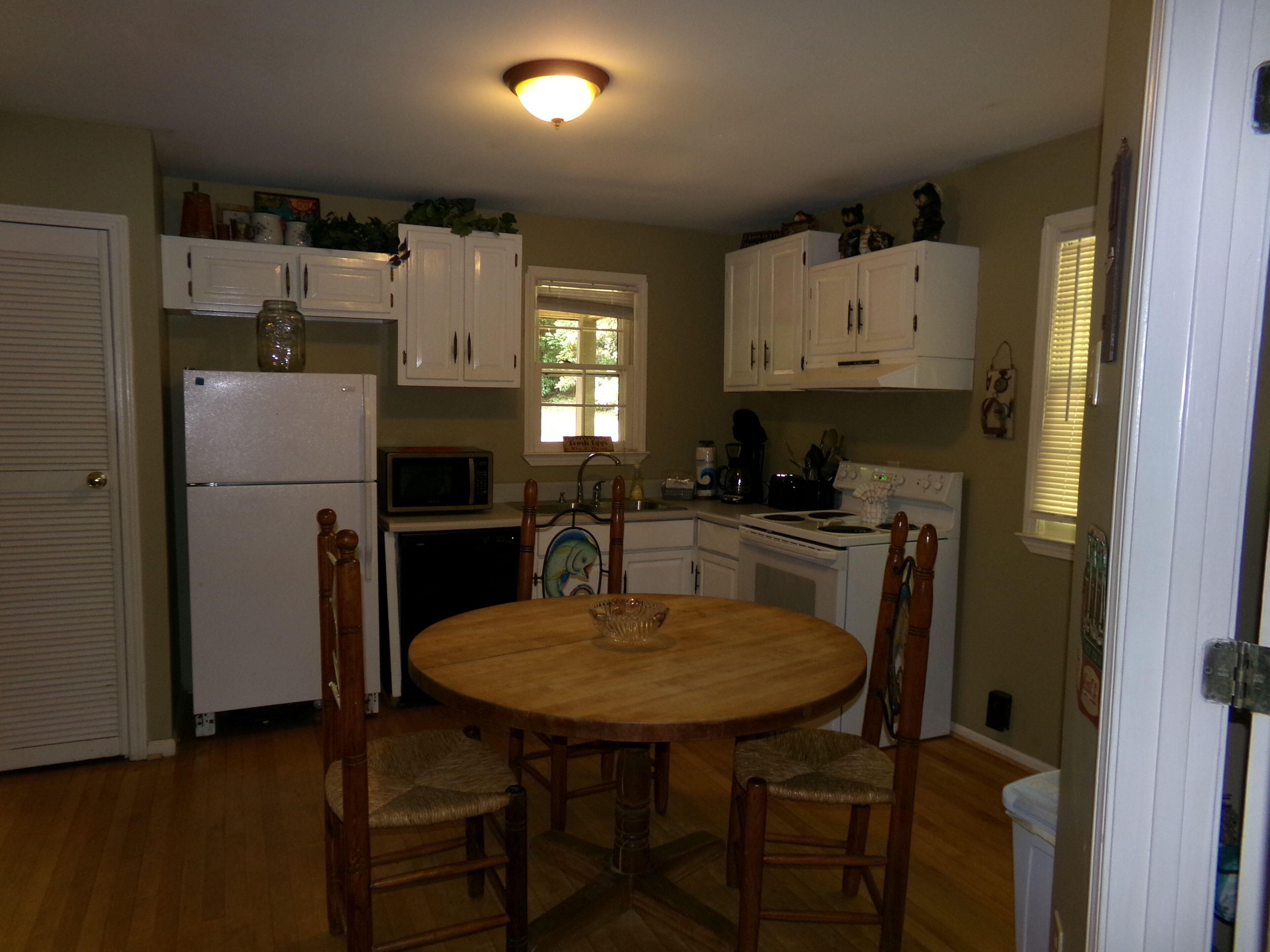 A kitchen with a wooden table and chairs, white cabinets, a refrigerator, a microwave, and a stove.