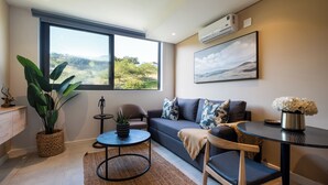 Uma sala de estar moderna com uma janela grande, um sofá, uma mesa de centro e um vaso com planta.