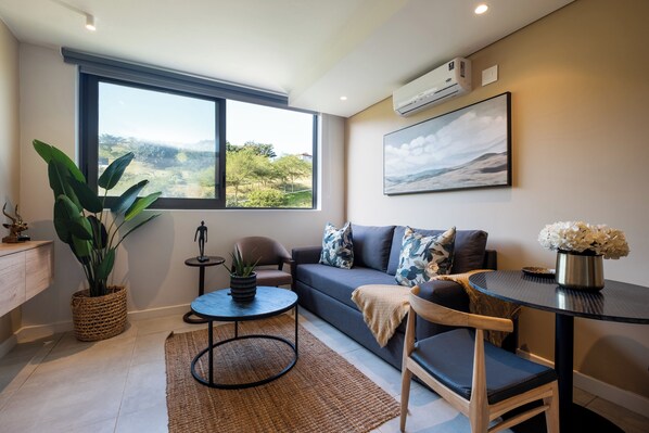 Una sala de estar moderna con un ventanal grande, un sofá, una mesa de centro y una planta en maceta.