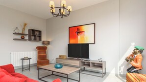 A modern living room with a sofa, coffee table, TV, and decorative items. - Amber 2-Bedroom Apartment in Jal El Dib  (Jal El Dib)