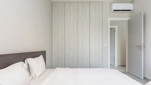 A hotel room with a bed, a headboard, an air conditioning unit, and a wardrobe. - Amber 2-Bedroom Apartment in Jal El Dib  (Jal El Dib)