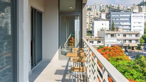 A balcony with a view of a cityscape, a hospital building, and a Baalbar sign. - Amber 2-Bedroom Apartment in Jal El Dib  (Jal El Dib)