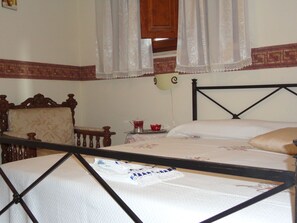 A bedroom with a wooden headboard, a bed with white linens, a nightstand with a red cup, and a wall-mounted lamp. - The House of Petra Modica (Modica)