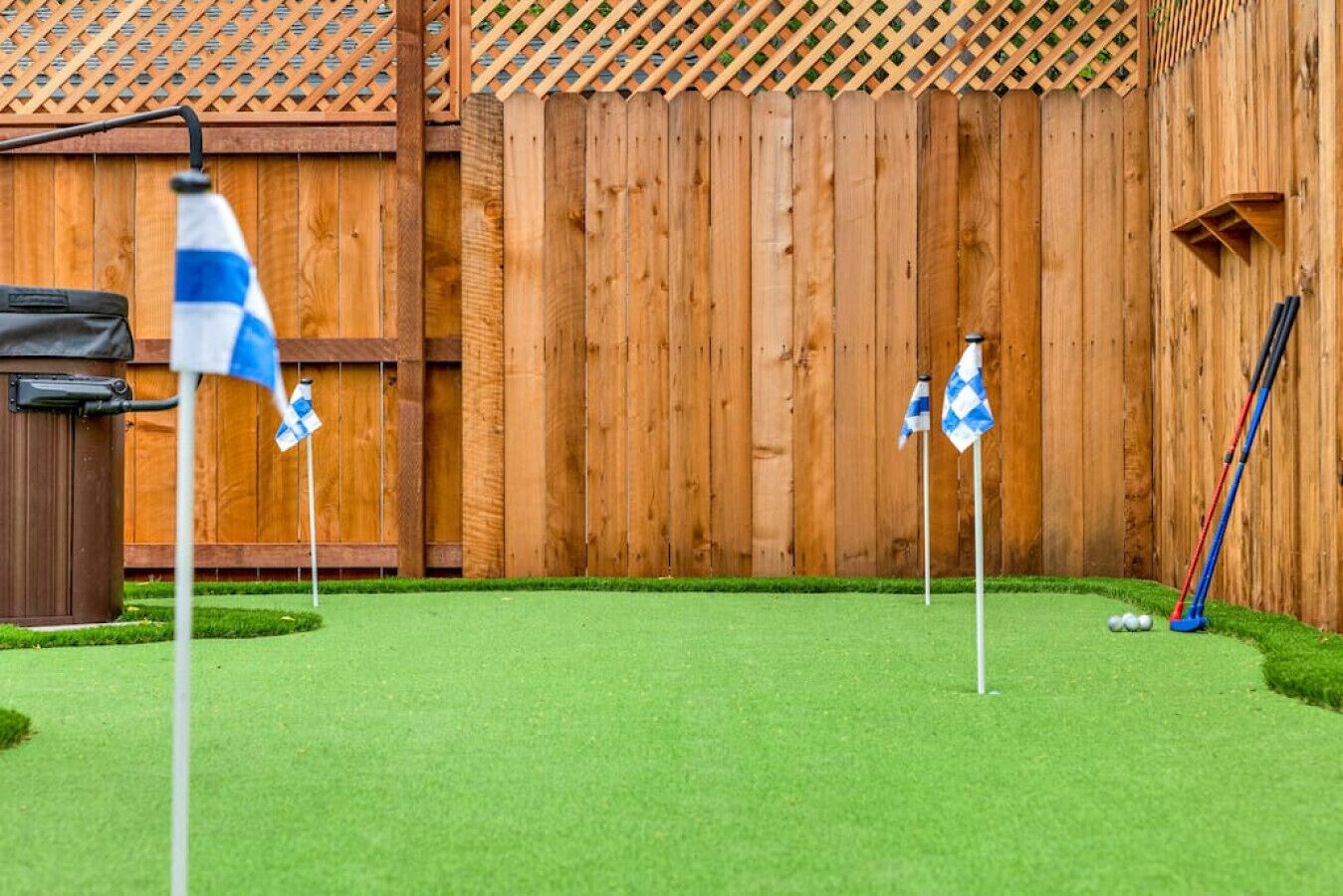 Un jardin avec une clôture en bois, une pelouse et des drapeaux de golf.