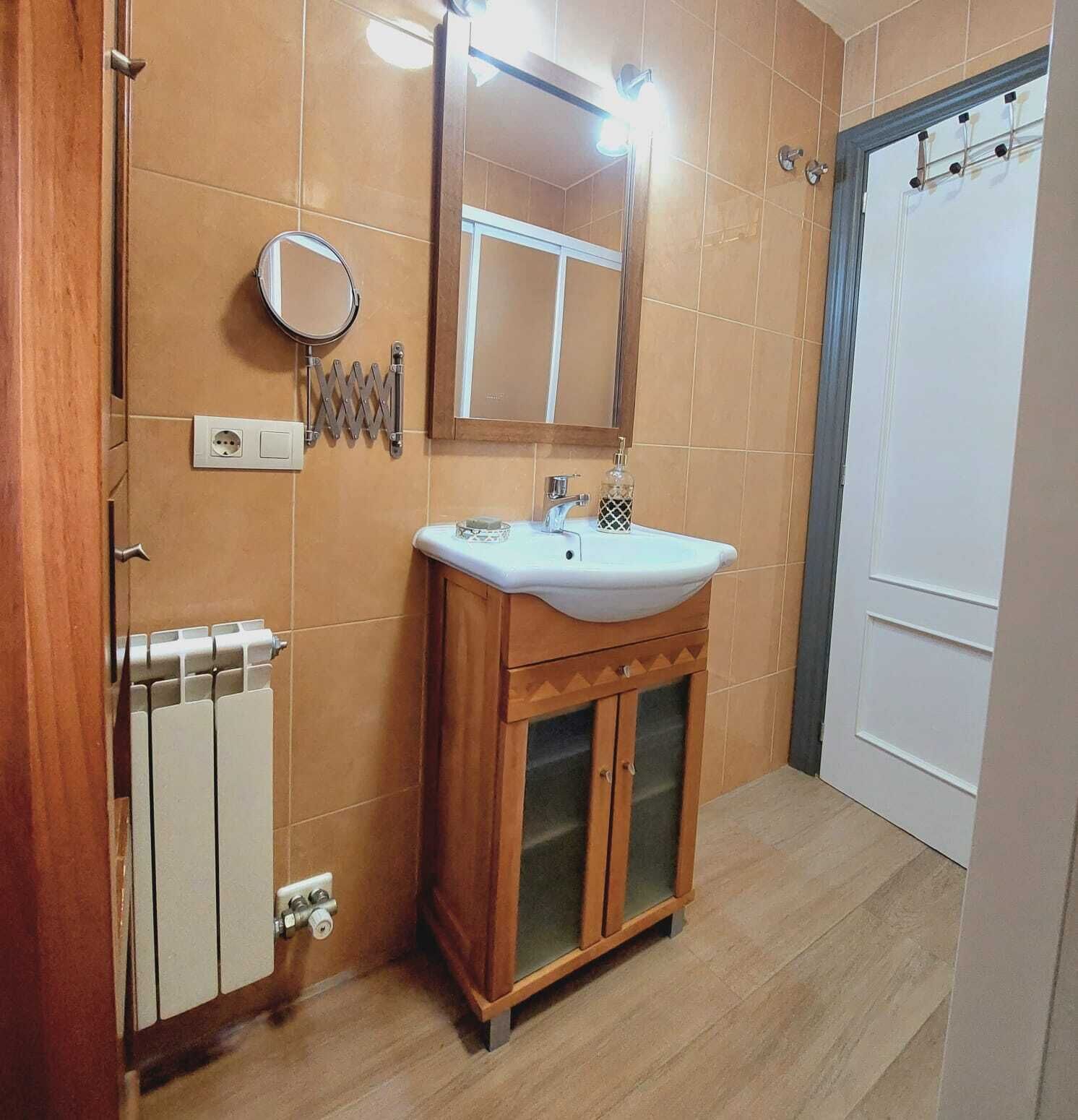 Une salle de bain avec un meuble-lavabo en bois, un lavabo blanc, un miroir et un radiateur.