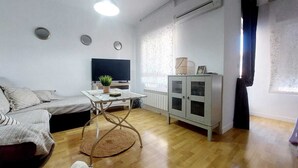 A living room with a sofa, a table with a plant, a cabinet, and a radiator.