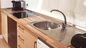 A modern kitchen with wooden cabinets, a stainless steel sink, and a black coffee maker.