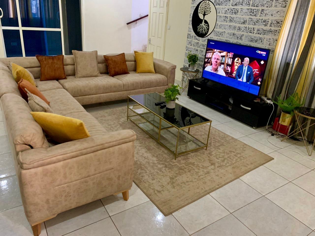 A living room with a beige sofa, a glass coffee table, and a television.
