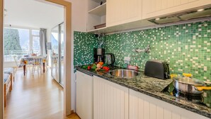 Une cuisine avec un plan de travail recouvert de carreaux verts, un évier en acier inoxydable, un grille-pain et une casserole sur la cuisinière.