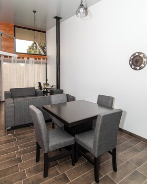 A dining area with a table and chairs, a sofa, a chimney, and a clock on the wall. - Arisa Mountain House (San Isidro)