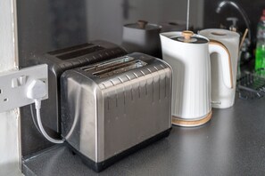 Ett kök med en brödrost, en vattenkokare och en kaffebryggare på bänkskivan.