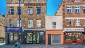 A street view with buildings including a Group Secure security service, a Flanx store, and an Alpino Italian snack bar. - Studio Unit in Chapel Market London (London)