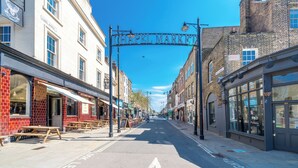 A street with a sign reading "CHAPEL MARKET" above a row of shops. - Studio Unit in Chapel Market London (London)