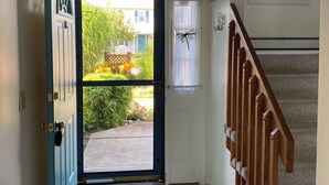 A hallway with a teal door, a wooden staircase, and a view of a garden outside. - Spacious beach house with front and back yards, short walk to Scarborough beach  (Narragansett)