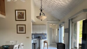 A spacious kitchen with white cabinets, a dining area with white chairs, and a ceiling fan. - Spacious beach house with front and back yards, short walk to Scarborough beach  (Narragansett)