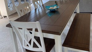 A dining area with a wooden table and white chairs, a television on a cabinet, and a ceiling fan. - Spacious beach house with front and back yards, short walk to Scarborough beach  (Narragansett)