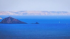 A coastal scene with a prominent rocky island and a distant shoreline. - Mew Stone - A large double room with extensive views out to sea. (Millbrook)