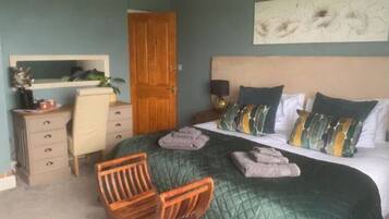 A bedroom with a bed, a chair, a dresser, a nightstand, and a door.