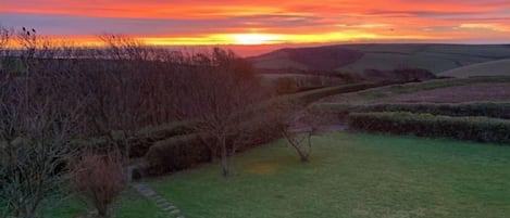 A rural landscape with rolling hills and a sunset.