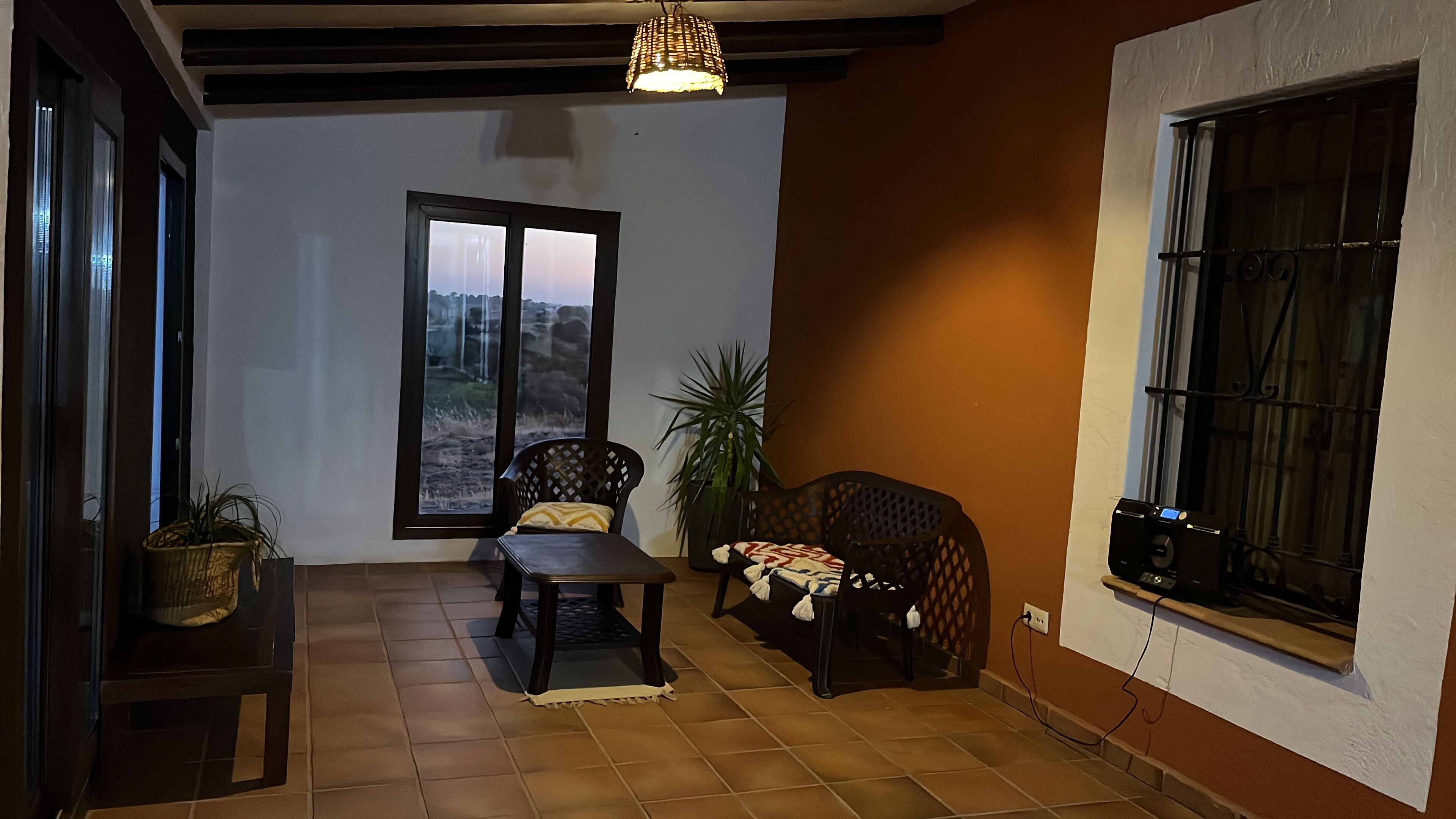 Un salon chaleureux avec un sol carrelé, un canapé, une table et une grande fenêtre donnant sur une cascade.