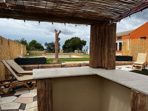 Un espace extérieur aménagé en terrasse, avec une pergola, des chaises longues et un mur en pierre.