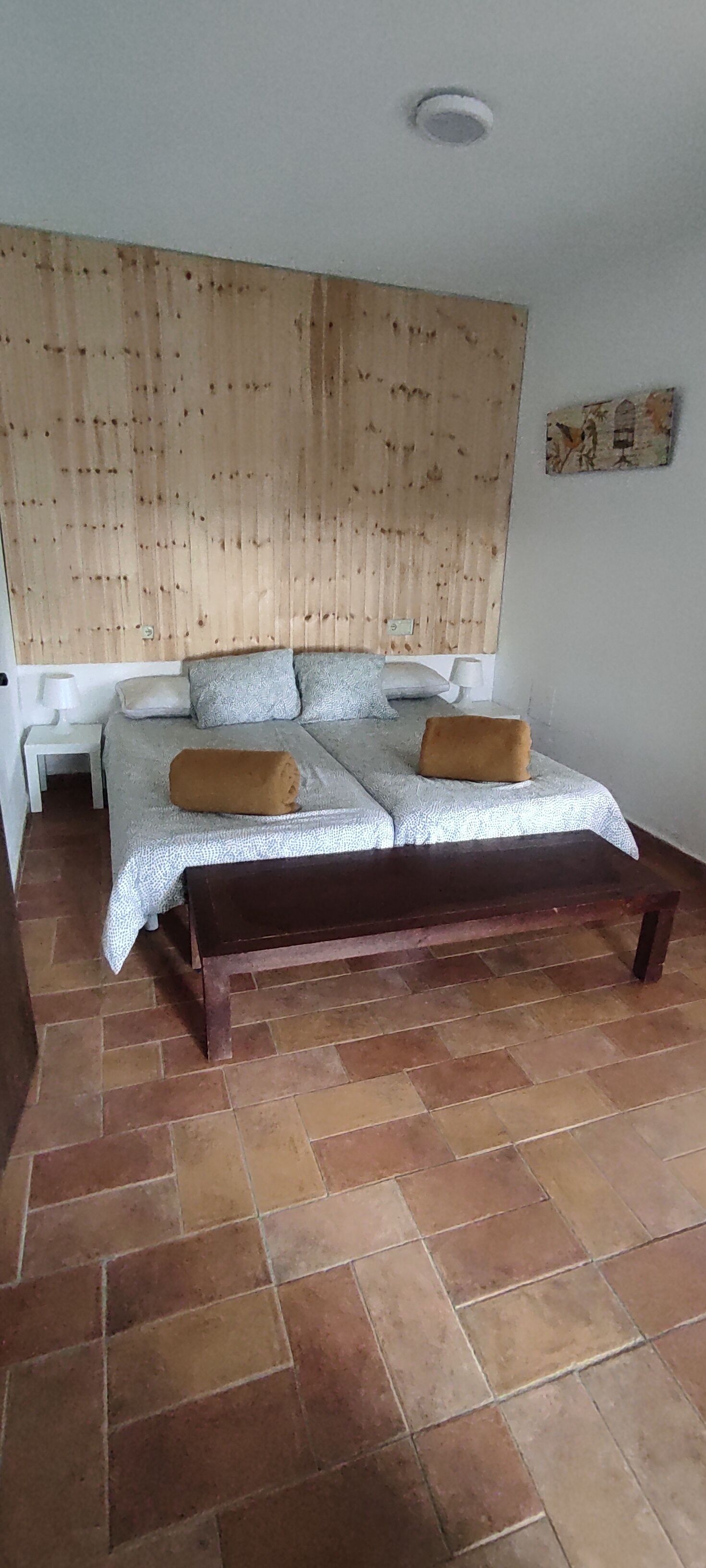 Ein Schlafzimmer mit einem Bett, zwei Kissen, einer Bank und einem Holzkopfseitenverkleidung.