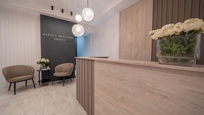 A reception area with a wooden reception desk, two chairs, and a vase of flowers. - Károly Boutique Suites, Best Location by BQA (Budapest)