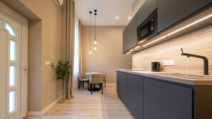 A modern kitchen with a central island, pendant lighting, and a built-in microwave. - Károly Boutique Suites, Best Location by BQA (Budapest)