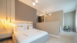 A modern hotel room with a large bed, bedside tables, a bedside lamp, and a small table with a vase of flowers. - Károly Boutique Suites, Best Location by BQA (Budapest)