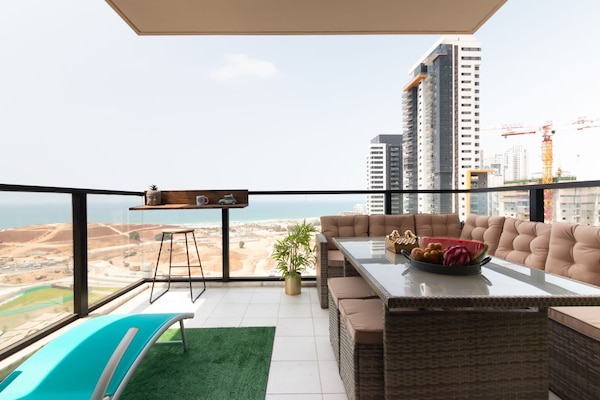 Spacious balcony lounge with sea views invites sunset dining and relaxed evenings near lively beach promenade.