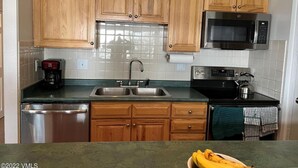 Una cocina con armarios de madera, lavavajillas de acero inoxidable, microondas y estufa.