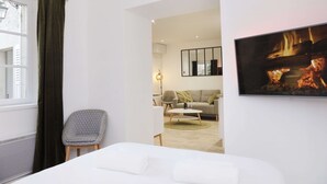Ein Hotelzimmer mit Bett, Sessel, Sofa, Fernseher und Kamin.