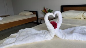 A hotel room with two beds, one with a heart-shaped towel decoration and a red flower. - Sunrise  (Drake Bay)