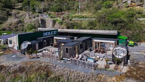 A building with a sign labeled 'HOLE37' featuring a patio area with outdoor seating and a pool. - HOLE37 (Tsukuba)